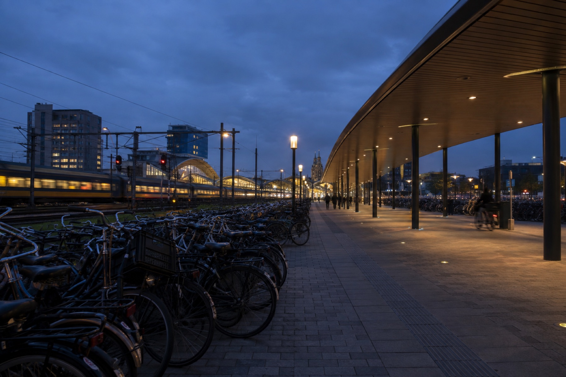 Perron bij schemer met rijen gestalde fietsen onder de overkapping