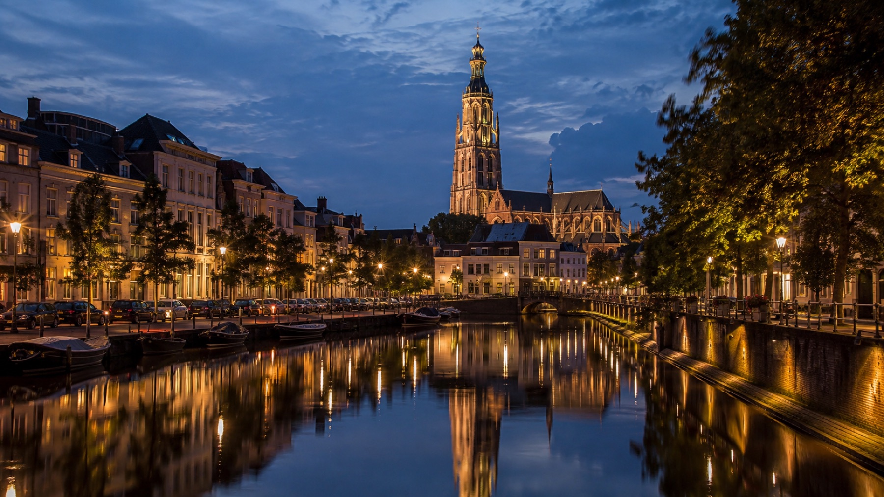 Gracht in Breda bij schemer, de toren van de Grote Kerk weerspiegeld in het water