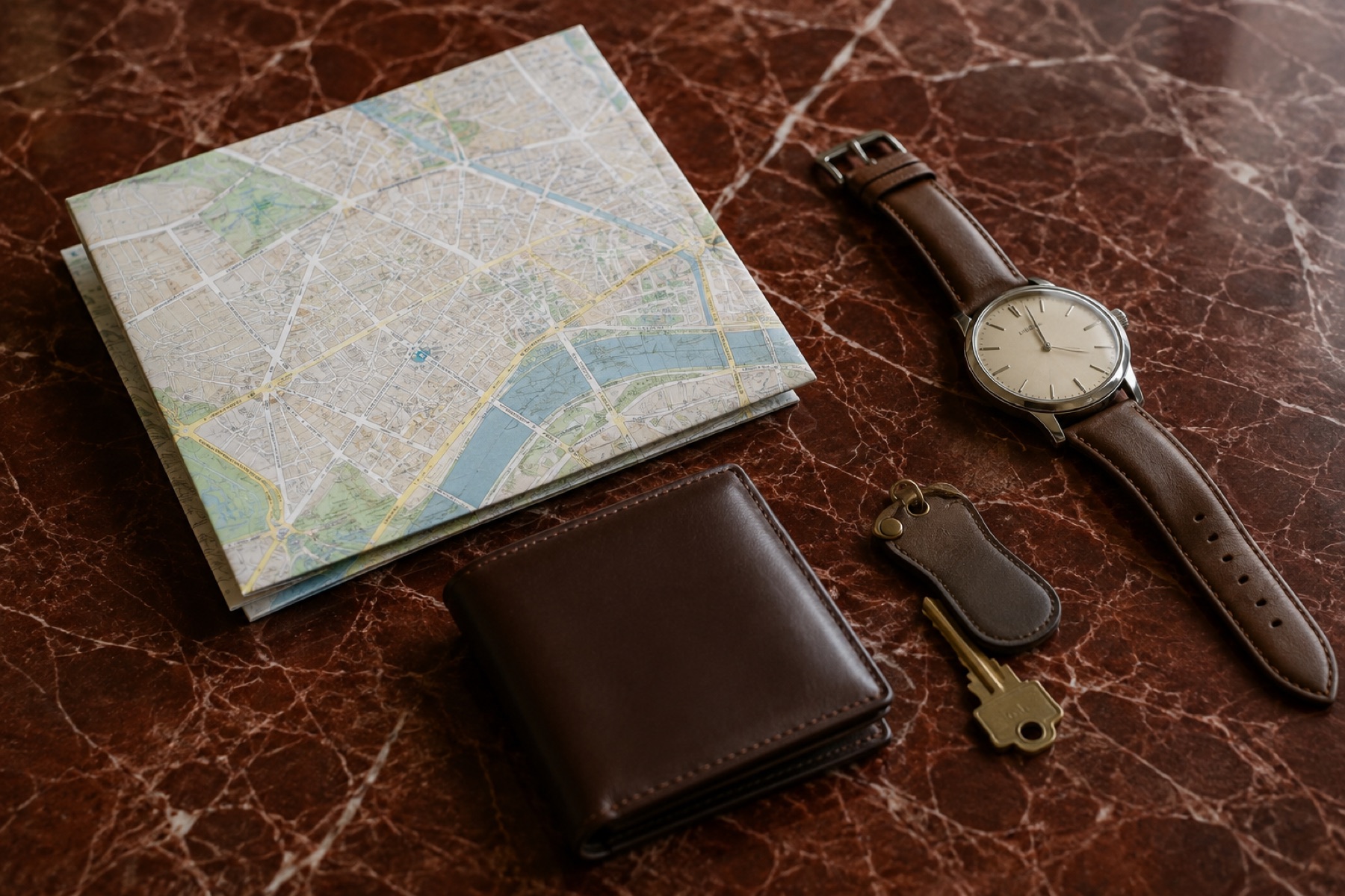 Stadsplattegrond, horloge, sleutels en portemonnee naast elkaar op een tafelblad